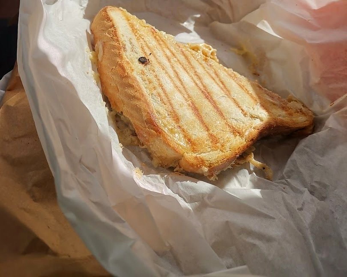 A grilled toastie with dark grill lines, in its white paper wrapping